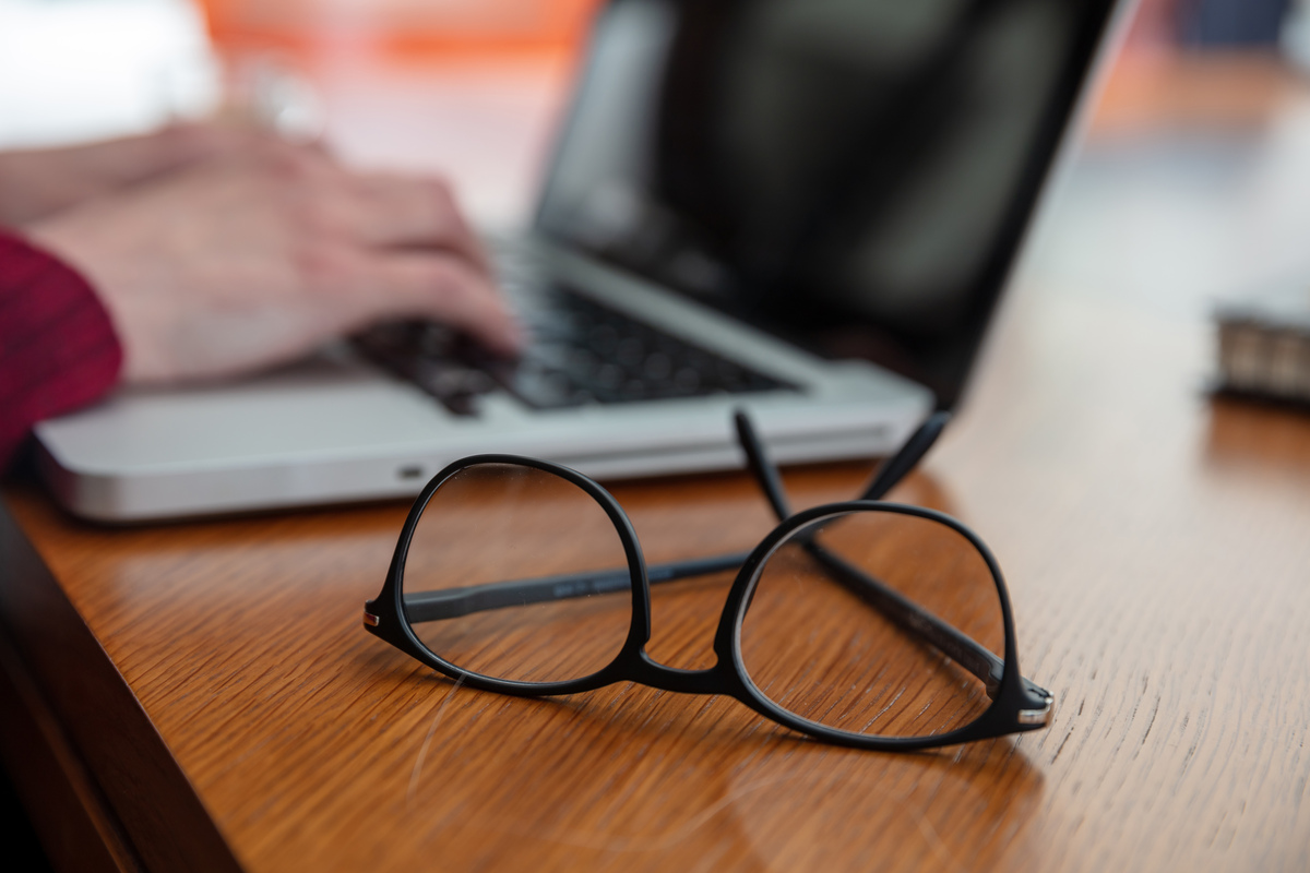 black frame eye glasses on a wooden office desk