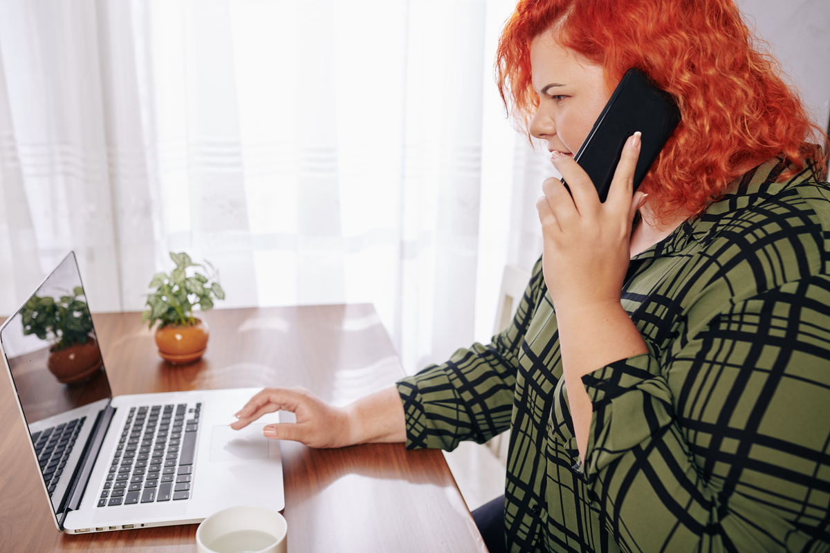 businesswoman reading something on her laptop and talking on the phone