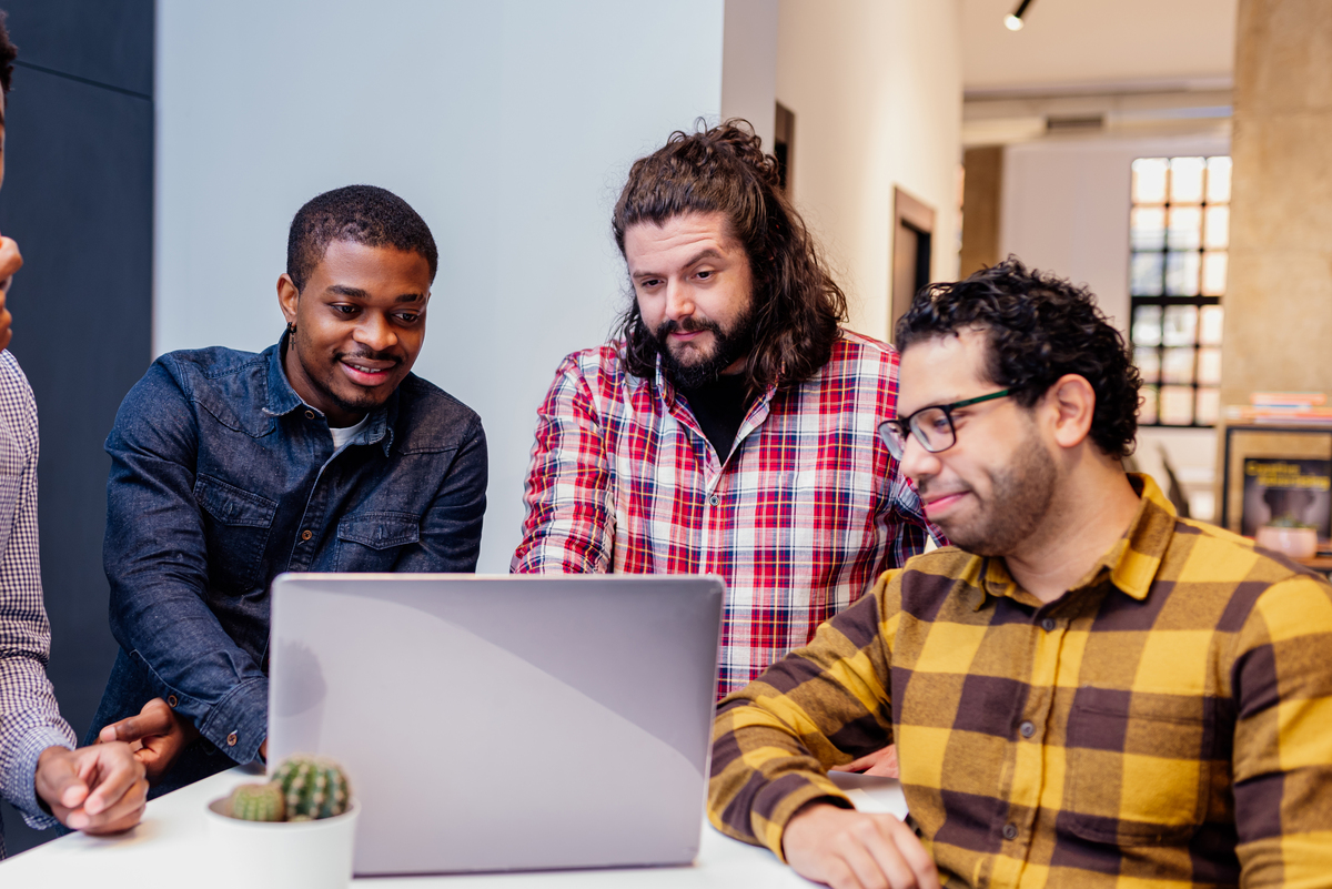 three men looking at a laptop