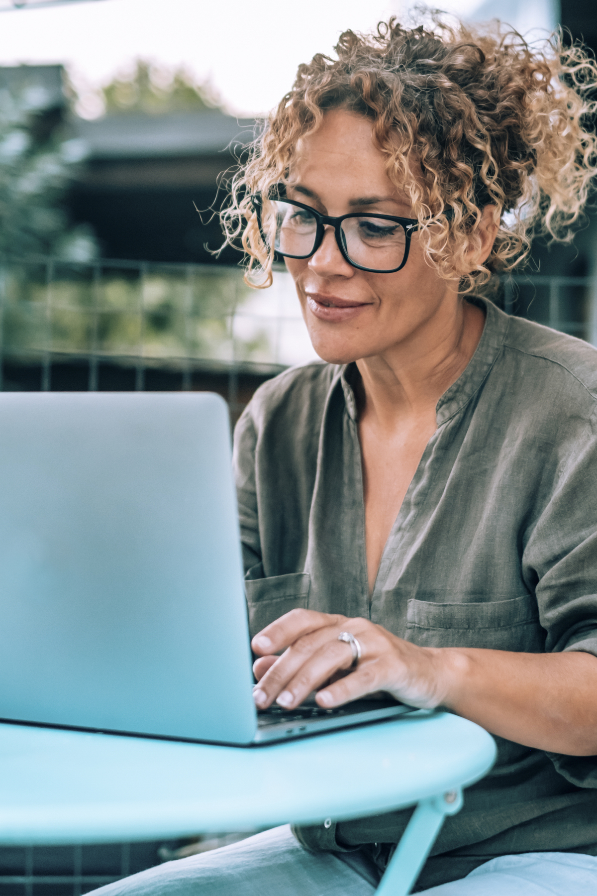 woman with glasses typing on a laptop