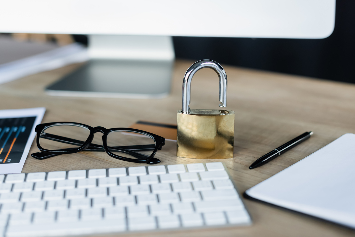 a table with a keyboard, glasses, a lock, pen and card on top