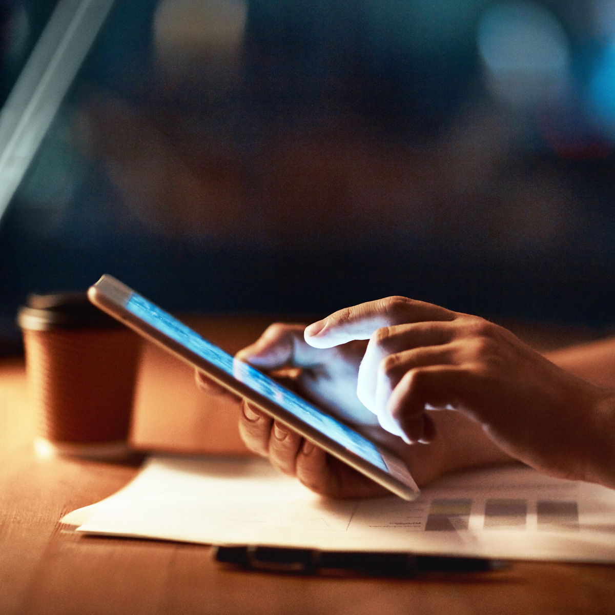 closeup of hands holding a tablet with a blue lit screen