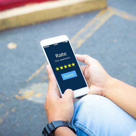 a person holding a cell phone, the screen says "rate you experience"