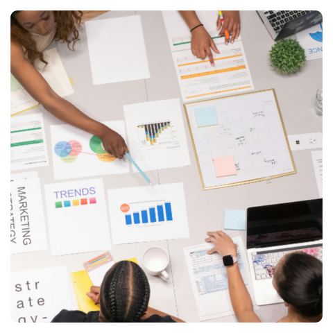 a group of people collaborating with a laptop and paper reports laid out on a table